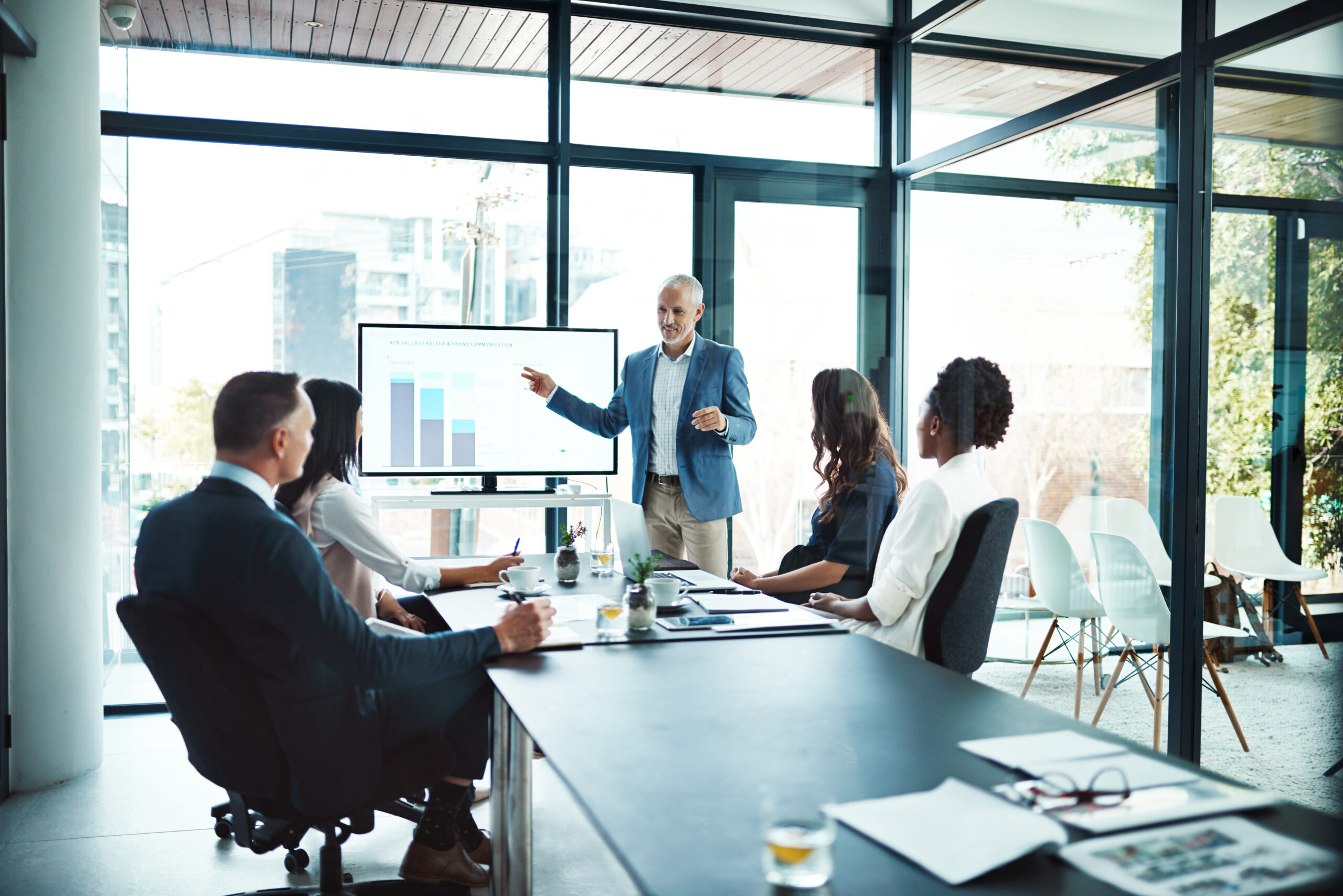 In a conference room, an accountant points to a chart while discussing financial forecasting versus value proposition budgeting.