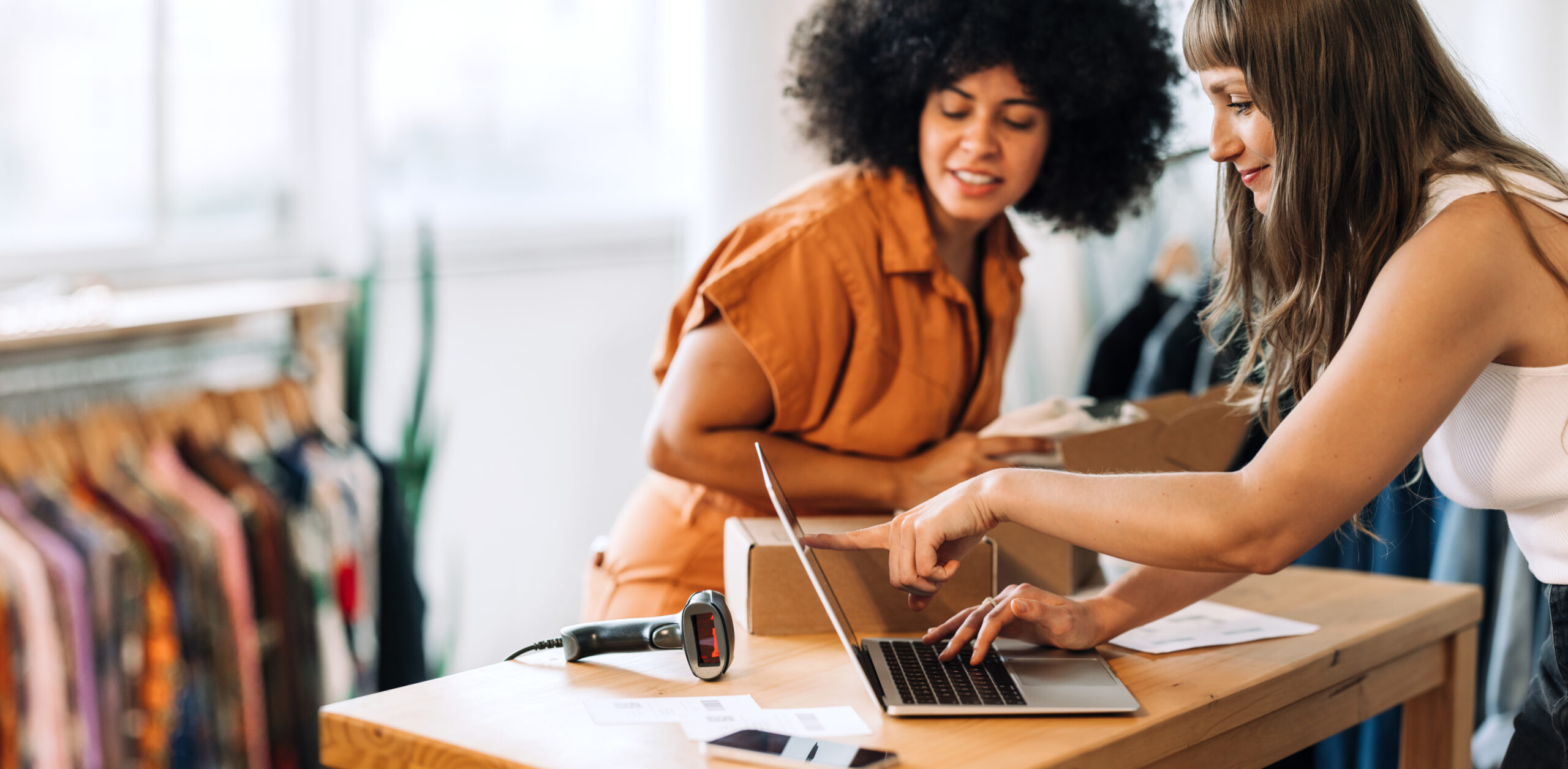 Two young women review financial reports showing small business growth