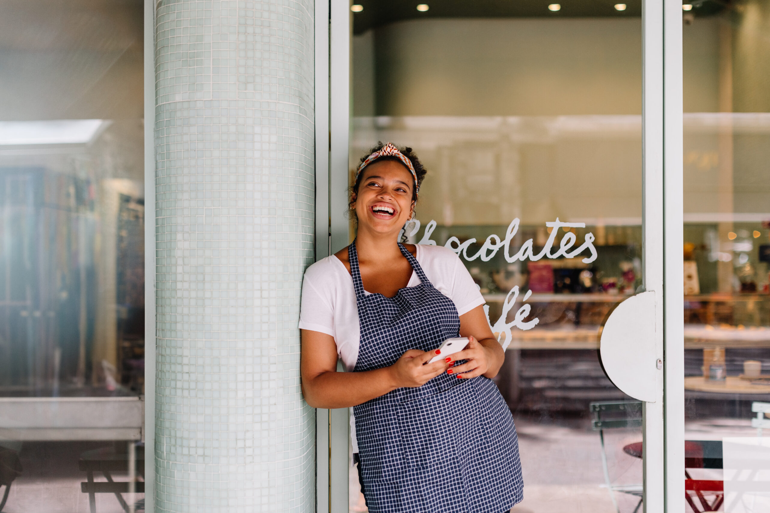 Smiling business owner standing outside of her shop after reading a small business insights article