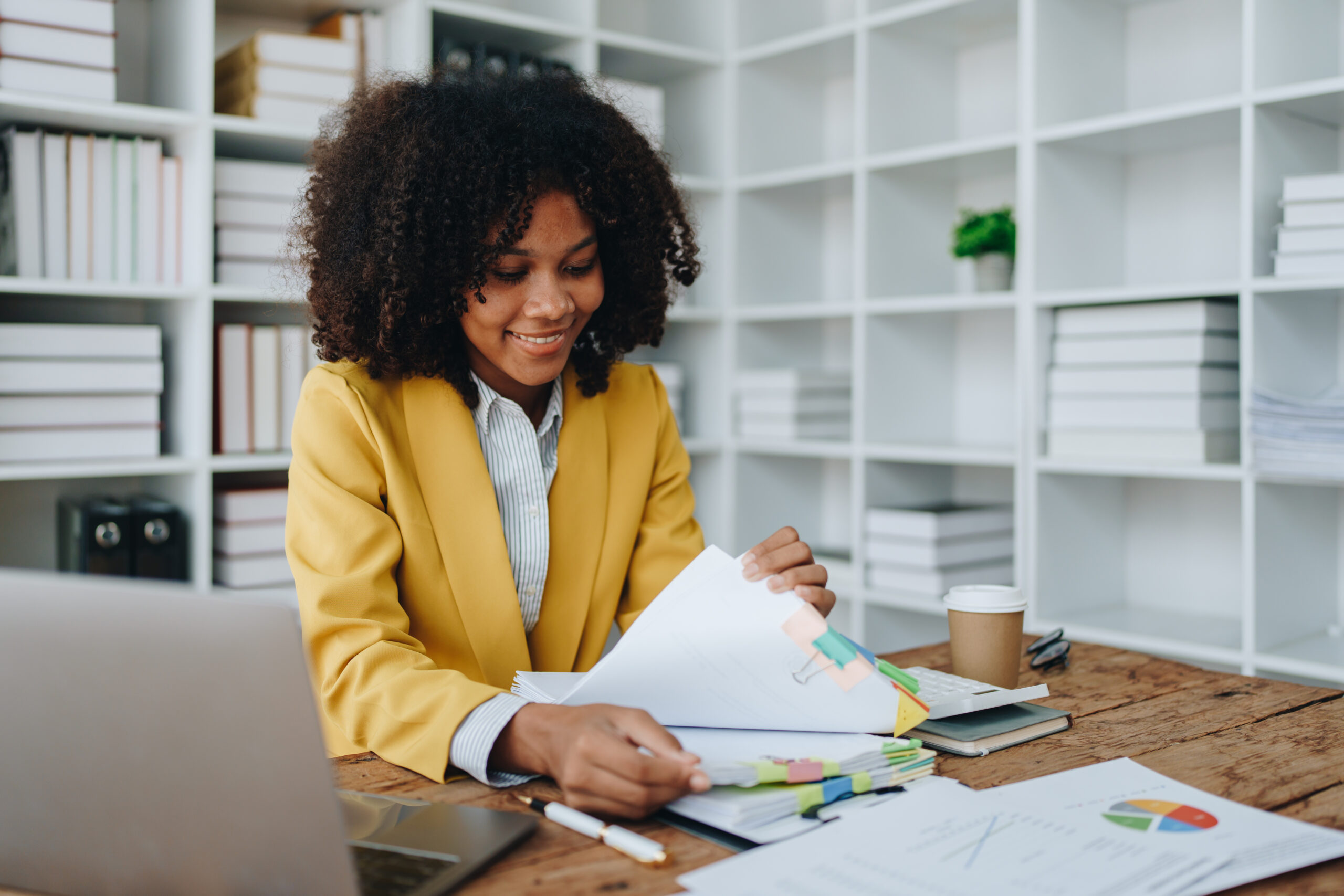 A smiling businessperson sits at a desk and works through an accounting checklist.