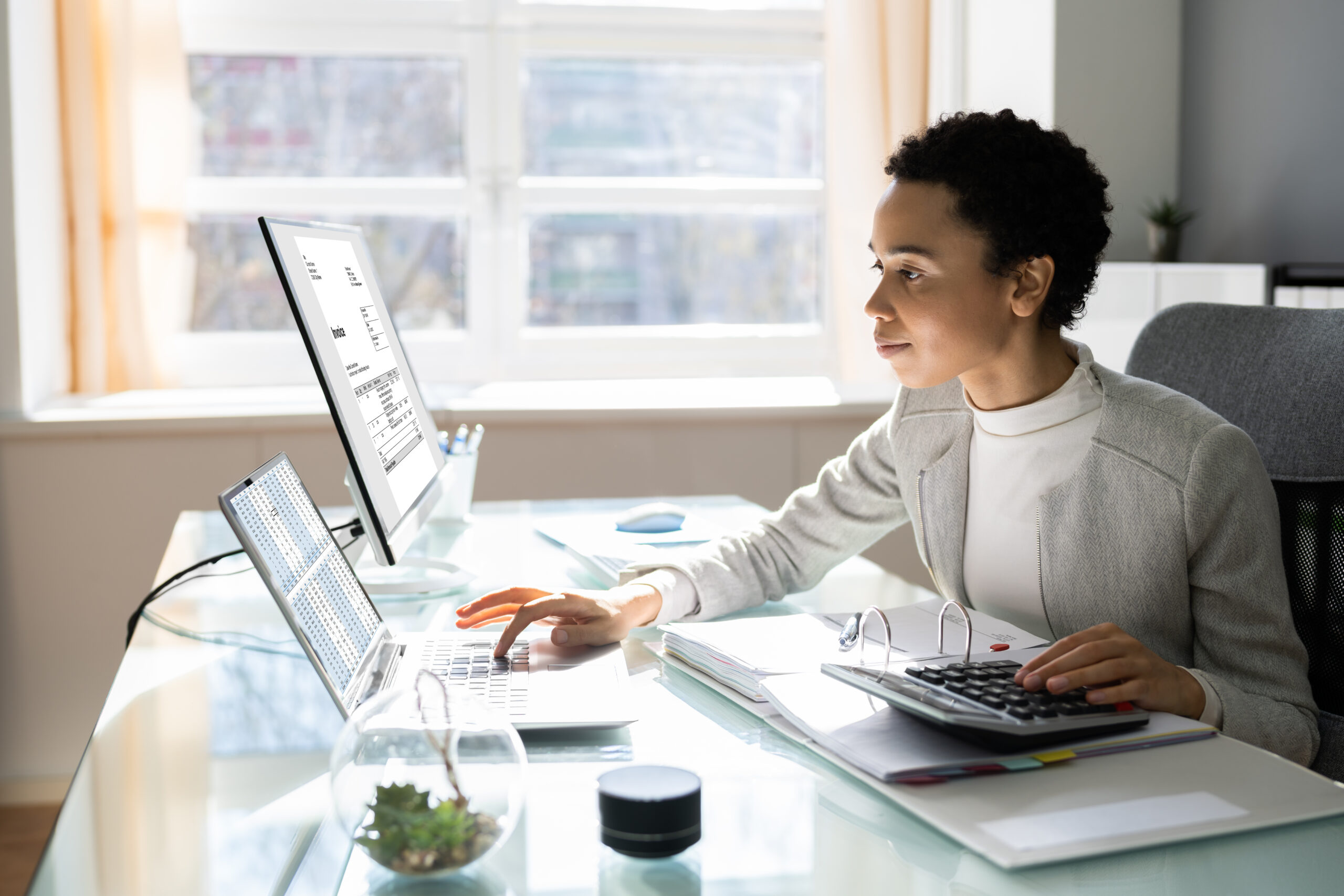 An accountant sits at a desk, looking at a laptop and reviewing a nonprofit audit.